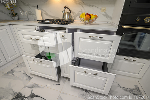 Image of Open drawers with kitchenware at modern white kitchen