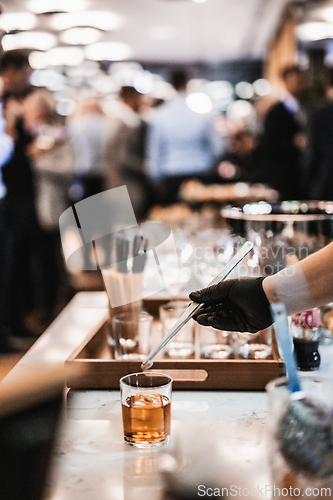 Image of Expert barman is making cocktail at business banquet event in hotel conference center. Blurred businesspeople at banquet event business meeting event in the background