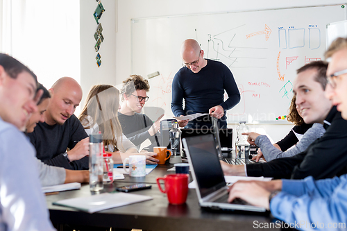 Image of Startup business and entrepreneurship problem solving. Young AI programmers and IT software developers team brainstorming and programming on desktop computer in startup company share office space.