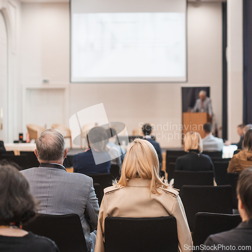 Image of Speaker giving a talk in conference hall at business event. Rear view of unrecognizable people in audience at the conference hall. Business and entrepreneurship concept.