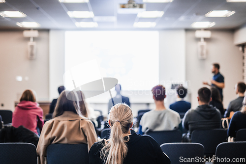 Image of Speaker giving a talk in conference hall at business event. Rear view of unrecognizable people in audience at the conference hall. Business and entrepreneurship concept.