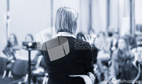 Image of Female public speaker giving talk at Business Event.