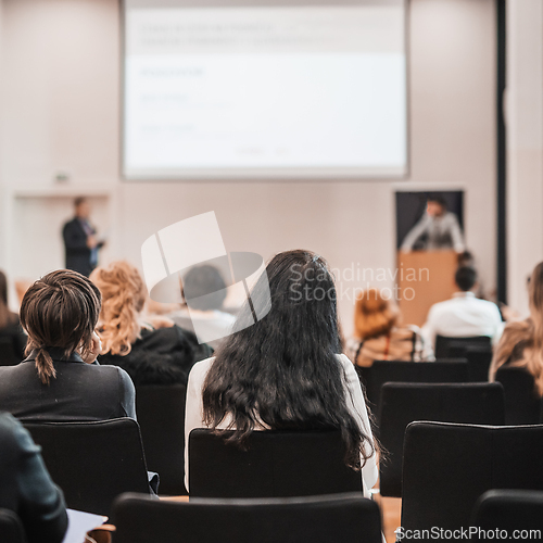 Image of Speaker giving a talk in conference hall at business event. Rear view of unrecognizable people in audience at the conference hall. Business and entrepreneurship concept.