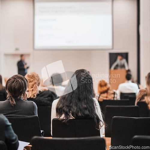 Image of Speaker giving a talk in conference hall at business event. Rear view of unrecognizable people in audience at the conference hall. Business and entrepreneurship concept.