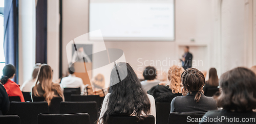 Image of Speaker giving a talk in conference hall at business event. Rear view of unrecognizable people in audience at the conference hall. Business and entrepreneurship concept.