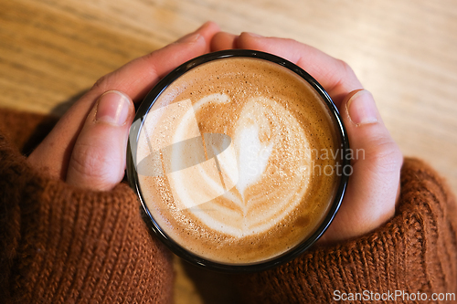 Image of Hands holding a cup of caffe latte