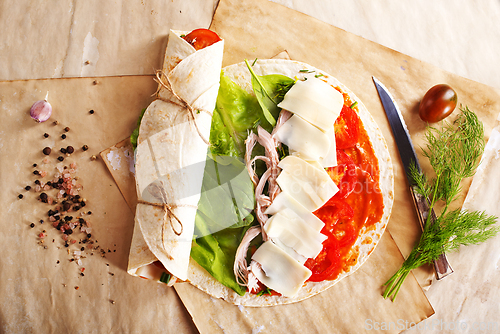 Image of Sliced sandwich tortilla with tomatoes , salad , cream cheese and ham .