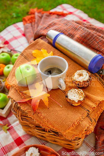 Image of Autumn picnic in a park with pumpkin cupcakes and muffins, coffee and tea