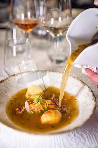 Image of Waiter pours broth into a bowl