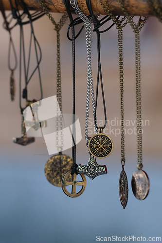 Image of Different necklaces and pendants ganing from a wooden pole 