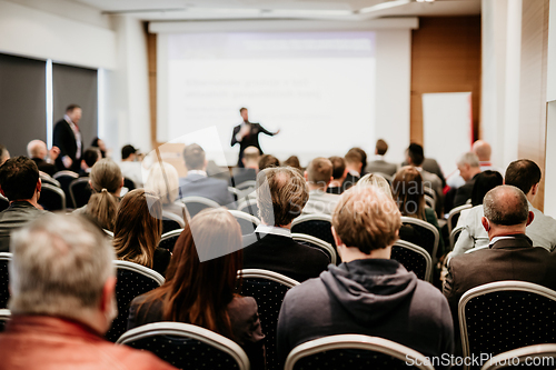 Image of Speaker giving a talk in conference hall at business event. Rear view of unrecognizable people in audience at the conference hall. Business and entrepreneurship concept.