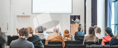 Image of Speaker giving a talk in conference hall at business event. Rear view of unrecognizable people in audience at the conference hall. Business and entrepreneurship concept.