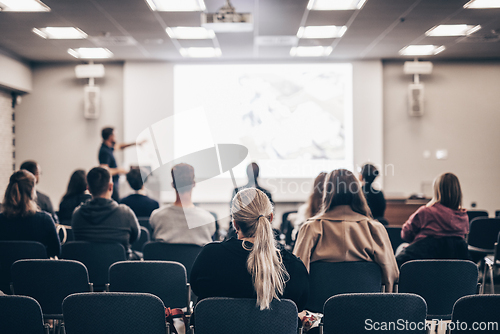 Image of Speaker giving a talk in conference hall at business event. Rear view of unrecognizable people in audience at the conference hall. Business and entrepreneurship concept.