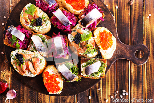 Image of Cocktail canapes with herring, cream cheese and caviar on rye bread