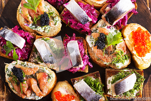 Image of Cocktail canapes with herring, cream cheese and caviar on rye bread