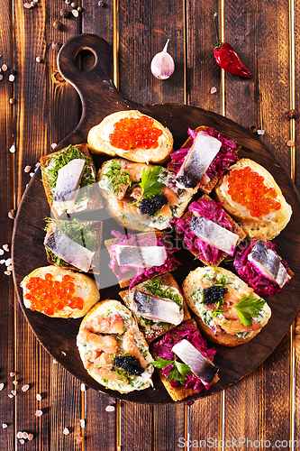Image of Cocktail canapes with herring, cream cheese and caviar on rye bread