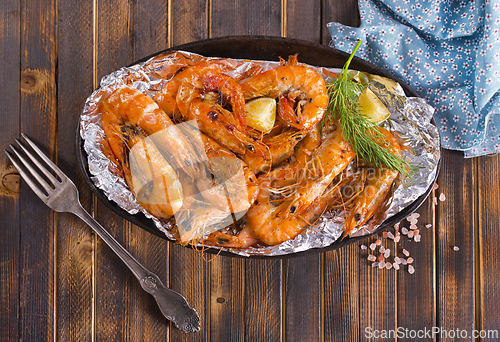Image of Roast Prawns Shrimps in a pan with herbs and garlic. Dark wooden background.