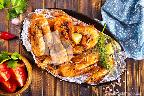 Image of Roast Prawns Shrimps in a pan with herbs and garlic. Dark wooden background.