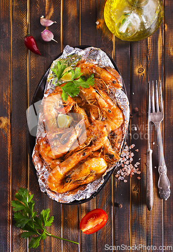 Image of Roast Prawns Shrimps in a pan with herbs and garlic. Dark wooden background.
