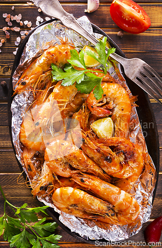 Image of Roast Prawns Shrimps in a pan with herbs and garlic. Dark wooden background.