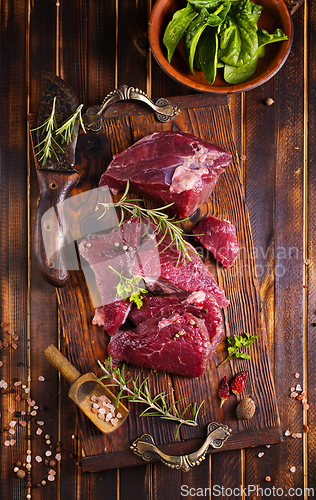 Image of Raw meat with herbs and garlic, marble meat. Wooden background. Top view.