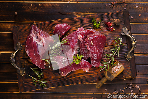 Image of Raw meat with herbs and garlic, marble meat. Wooden background. Top view.