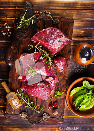 Image of Raw meat with herbs and garlic, marble meat. Wooden background. Top view.