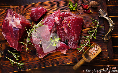 Image of Raw meat with herbs and garlic, marble meat. Wooden background. Top view.