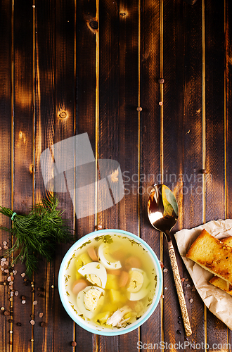 Image of Egg drop soup with meat in white porcelain bowl on wooden table. Fresh soup with eggs and vegetable