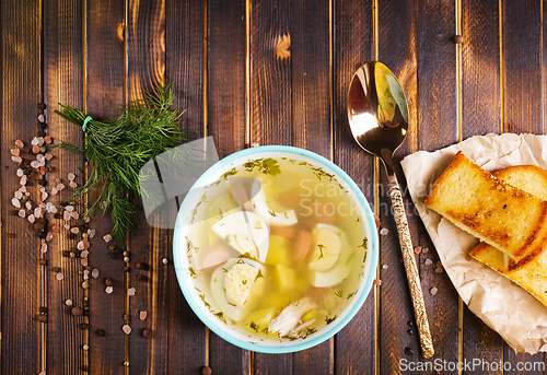 Image of Egg drop soup with meat in white porcelain bowl on wooden table. Fresh soup with eggs and vegetable