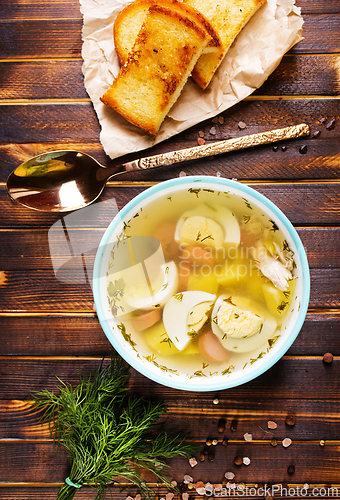Image of Egg drop soup with meat in white porcelain bowl on wooden table. Fresh soup with eggs and vegetable