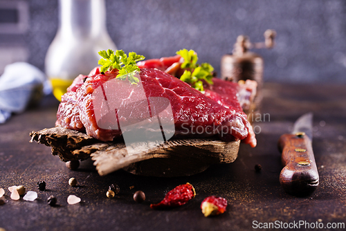Image of Raw meat with herbs and garlic, marble meat. Wooden background. Top view.