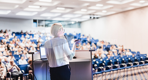 Image of Female speaker giving a talk on corporate business conference. Unrecognizable people in audience at conference hall. Business and Entrepreneurship event.