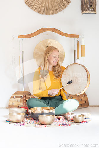 Image of Young cheerful woman performing music therapy session with traditional instruments. Sound meditation, body healing. Seven chakras. Healthcare recreation process.