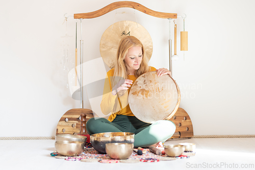 Image of Young cheerful woman performing music therapy session with traditional instruments. Sound meditation, body healing. Seven chakras. Healthcare recreation process.