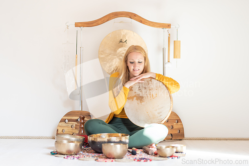 Image of Young cheerful woman performing music therapy session with traditional instruments. Sound meditation, body healing. Seven chakras. Healthcare recreation process.