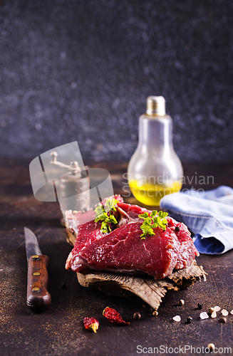 Image of Raw meat with herbs and garlic, marble meat. Wooden background. Top view.