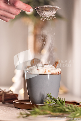 Image of Chef sprinkling icing sugar on delicious Christmas hot chocolate