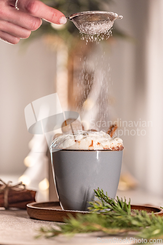 Image of Chef sprinkling icing sugar on delicious Christmas hot chocolate