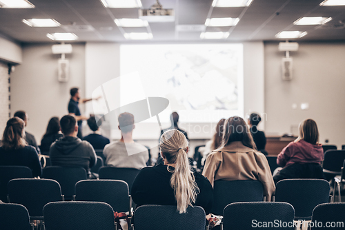 Image of Speaker giving a talk in conference hall at business event. Rear view of unrecognizable people in audience at the conference hall. Business and entrepreneurship concept.