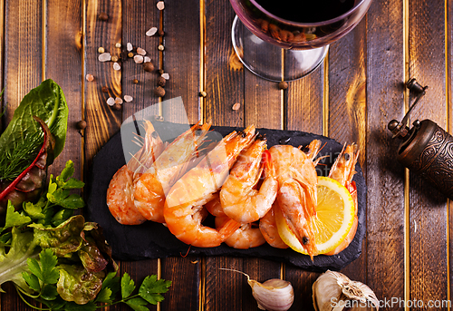 Image of Fried shrimps with garlic, lemon served on black plate on wooden table