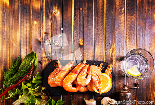 Image of Fried shrimps with garlic, lemon served on black plate on wooden table