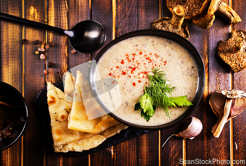 Image of Bowl of creamy mushroom soup, sliced mushrooms and parsley with bread
