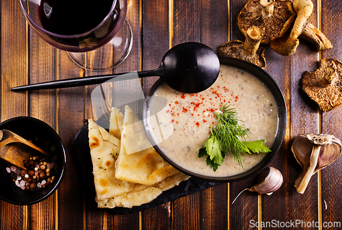 Image of Bowl of creamy mushroom soup, sliced mushrooms and parsley with bread