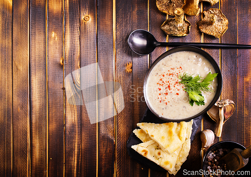 Image of Bowl of creamy mushroom soup, sliced mushrooms and parsley with bread
