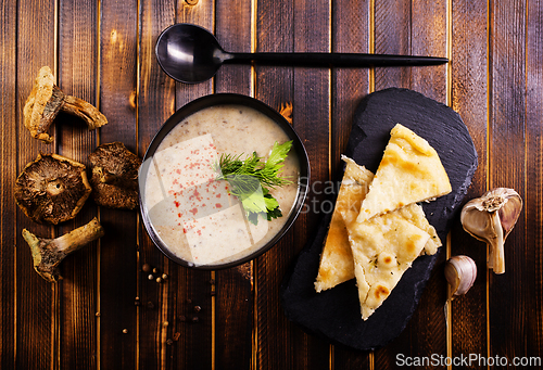 Image of Bowl of creamy mushroom soup, sliced mushrooms and parsley with bread