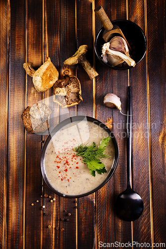 Image of Bowl of creamy mushroom soup, sliced mushrooms and parsley with bread