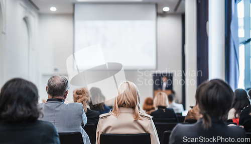 Image of Speaker giving a talk in conference hall at business event. Rear view of unrecognizable people in audience at the conference hall. Business and entrepreneurship concept.