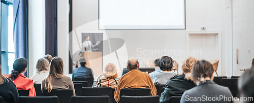 Image of Speaker giving a talk in conference hall at business event. Rear view of unrecognizable people in audience at the conference hall. Business and entrepreneurship concept.