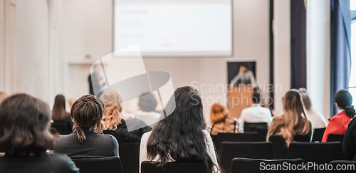 Image of Speaker giving a talk in conference hall at business event. Rear view of unrecognizable people in audience at the conference hall. Business and entrepreneurship concept.